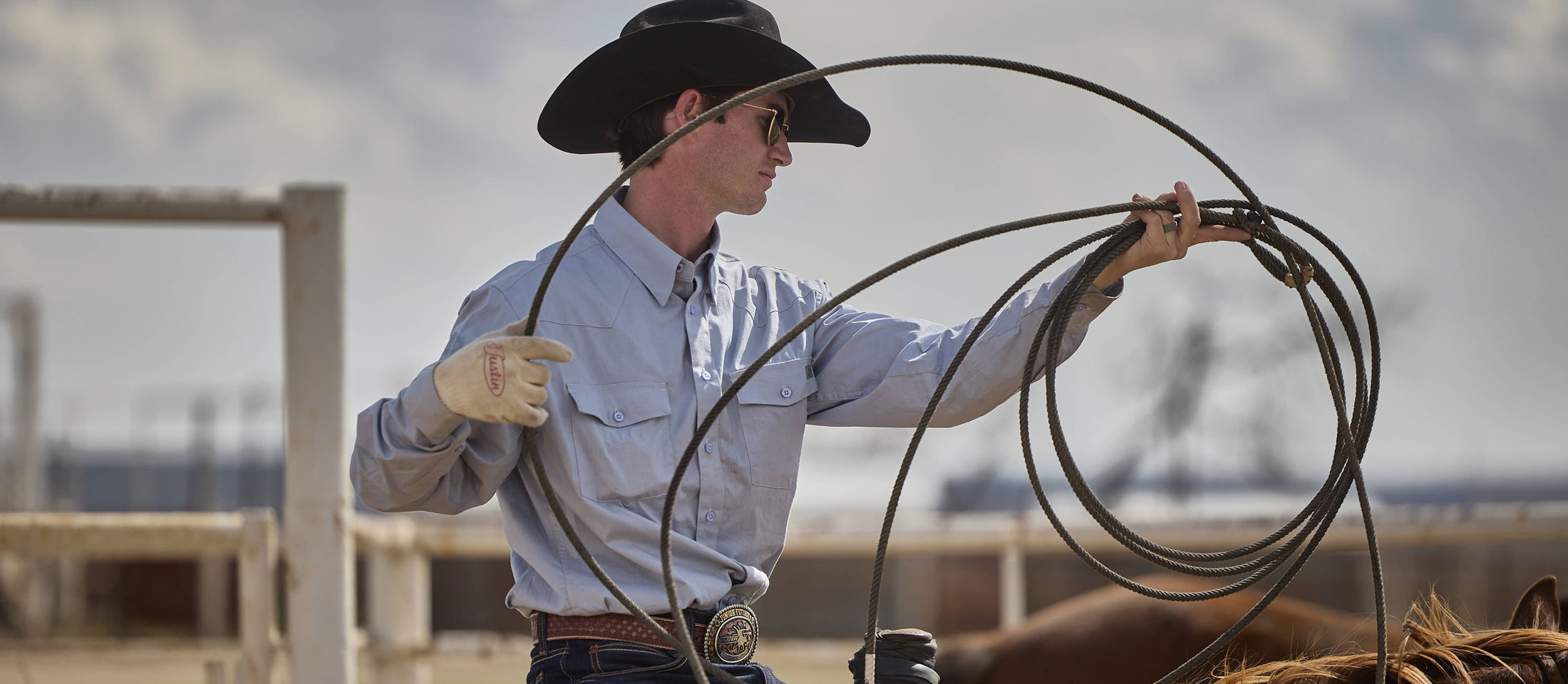 A cowboy holding a lasso while wearing a black cowboy hat.